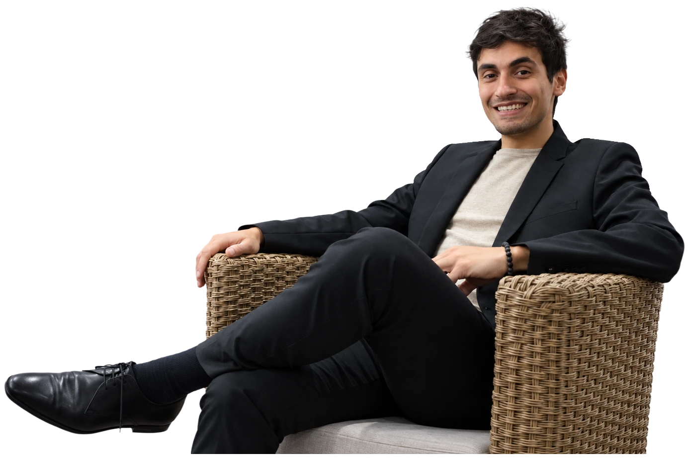 Yago Ribeiro, fondateur de Finesty à Genève, spécialiste en finance et comptabilité avec brevet fédéral, assis dans un fauteuil en rotin, veste noire sur t-shirt clair